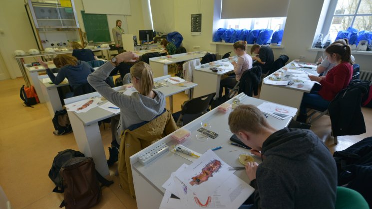 Õpilased istuvad klassiruumis valgete laudade taga ja lahendavad bioloogia ülesandeid.