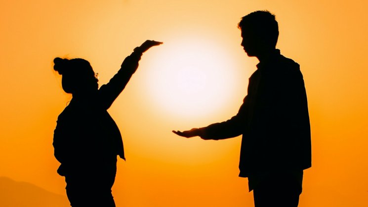 Naine ja mees seisavad oranžil taustal päike toetatud mehe käele.